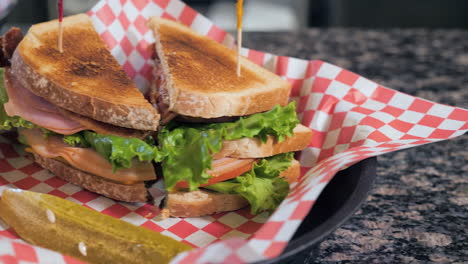 Club-Sandwich-with-pickle-on-red-checkered-paper-in-basket,-slider-slow-motion-HD