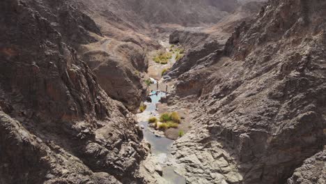 Group-of-friends-enjoy-a-beautiful-sunny-day-and-explore-the-freshwater-pools-in-the-middle-of-a-dry-arid-wadi-valley