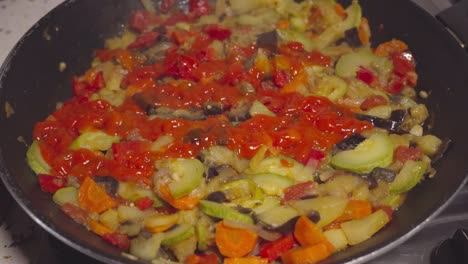 Adding-tomato-paste-to-Spanish-pisto-and-stirring,-Closeup-on-Hand-and-Pan
