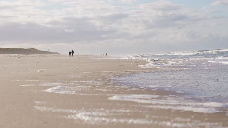 Silhouettes-of-couple-walking-in-slow-motion-on-sandy-Sylt-beach-in-Germany