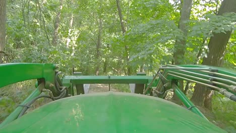POV-of-equipment-operator-driving-a-loader-with-forks-driving-on-a-trail-thru-the-woods-on-a-sunny-day-in-Illinois