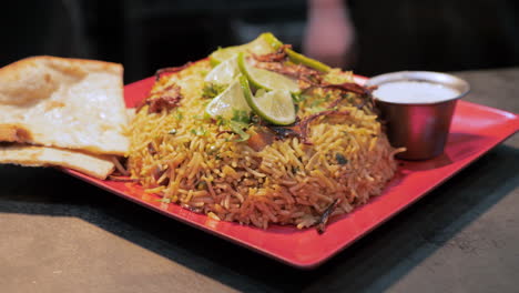 Pile-of-biryani-topped-with-chilies-and-limes-traditional-Indian-dish,-orbit-slider-slow-motion-HD