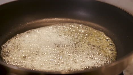 Close-up-of-butter-frying-in-a-pan---handheld