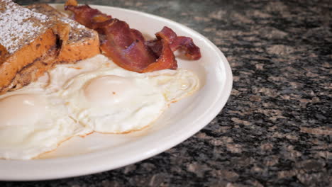 Diner-breakfast-on-white-plate,-French-toast-fried-eggs-and-bacon----slider-HD