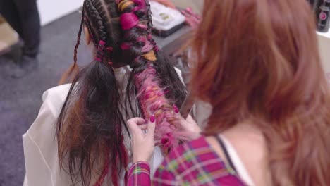Ginger-hairdresser-is-Brading-and-tidying-up-colourful-braids-slow-motion