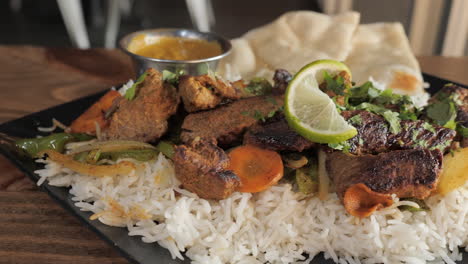 Traditional-plated-tandoori-kabob-with-steak-veggies-over-basmati-rice-with-naan,-slow-motion-slider-close-up-4K