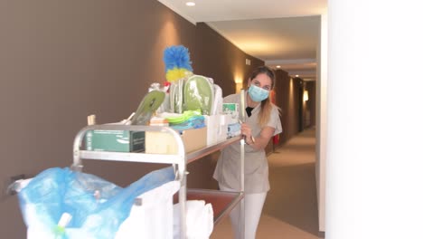 Zimmermädchen-Mit-Gesichtsmaske-Und-Bodenwagen-Geht-Durch-Einen-Korridor-Im-Hotel