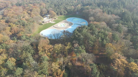 Aerial-reveal-of-deserted-outdoor-swimming-pool-surrounded-by-forest