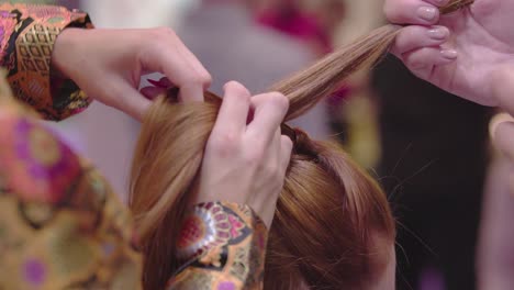 close-up-of-hairdresser-with-fashionable-jacket-red-nails-creating-hairstyle-on-brunette-female-slow-motion