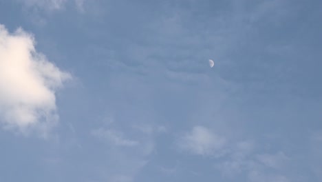 Moon-in-its-first-quarter-time-lapse-as-seen-before-dark-with-clouds-almost-covering-it-on-the-right-side-of-the-frame