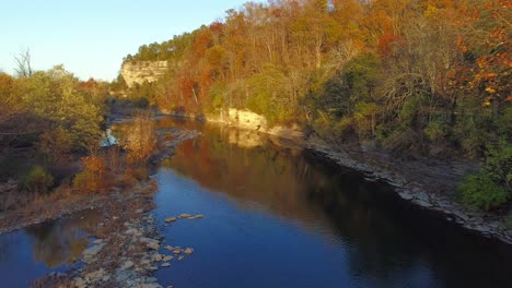 Aerial-shot-traveling-down-Elkhorn-Creek-in-the-fall-cliff-reflecting-off-the-water