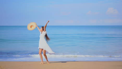 A-pretty-young-woman-walking-along-a-sandy-beach-toward-the-sea-reacts-in-joy-by-twirling-around-in-circles