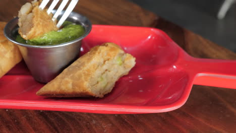 Fork-picks-up-samosa-and-dips-into-bright-green-chutney,-slider-slow-motion-close-up-HD