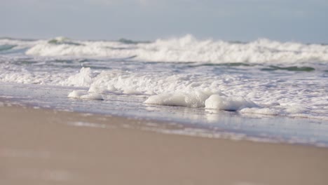 Breaking-waves-washing-up-white-foam-on-sandy-Sylt-beach-in-Germany