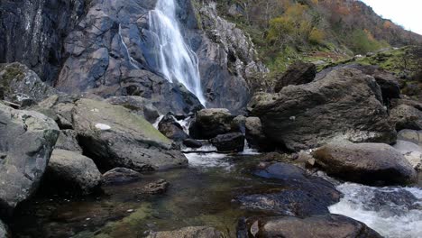 Rocky-cascading-waterfall-rushing-into-jagged-river-rocks-and-boulders-time-lapse