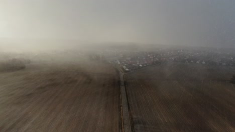 Aerial-Road-Between-Brown-Ground-Field-During-Blizzard-4K