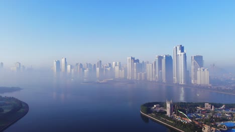 Blick-Von-Oben-Auf-Den-Khalid-See-Von-Sharjah,-Die-Skyline-Von-Sharjah-An-Einem-Nebligen-Morgen,-Nebel-Im-Golf,-Vereinigte-Arabische-Emirate,-4K-Video
