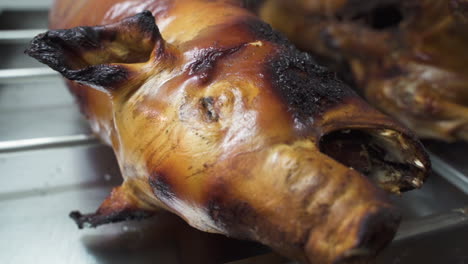 Detail-of-roasted-piglet's-head-on-restaurant-stand---B-roll---Close-up-slow-motion