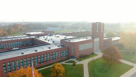 Aerial-pullback-reveals-American-flag-at-large-brick-school-building