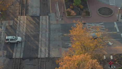 Overhead-view-of-cars-crossing-railroad-tracks-at-an-intersection-in-Kirkwood-Missouri-in-Autumn-at-golden-hour