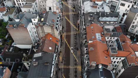 Aerial-forwarding-flight-while-drone-is-following-white-car-in-Brussels'-streets,-Belgium