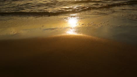 Friedliche-Wellen,-Die-Während-Des-Sonnenuntergangs-über-Glatten,-Nassen-Sand-Rollen---Nahaufnahme