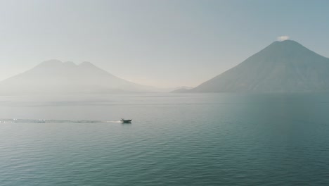 Drone-aerial,-boat-driving-over-lake-Atitlan-during-the-morning-in-Guatemala