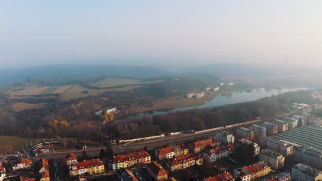 Aerial-Over-Motorway-Beside-Lake-With-Fields-Nearby-With-Morning-Mist