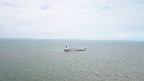 Cargo-ship-in-the-middle-of-the-sea-with-no-other-ships-around-cloudy-day-drone-shot