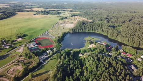 Aerial-Overview-of-Lake-next-to-Stadium-with-Forest-in-Background