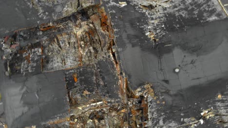 Aerial-view-of-roof-surface-severely-damaged-by-fire,-rotating-shot