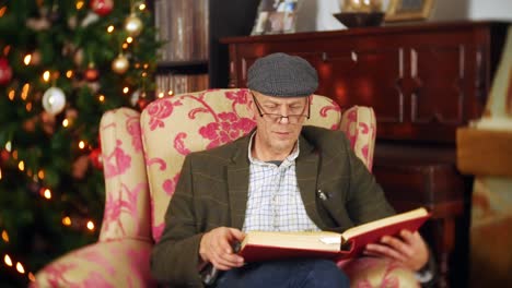 A-senior-man-is-reading-a-festive-Christmas-story-from-a-large-red-book
