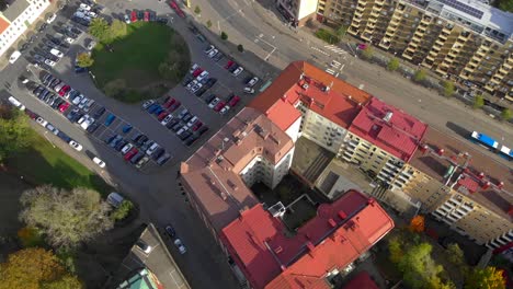 Aerial-view-of-city-with-buildings,-car-park-and-buses-on-urban-road