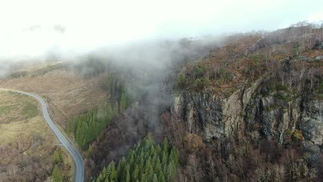 Aerial-View-of-Scenic-Landscape-and-Morning-Fog-Above-Cliffs,-Forest-and-Road-in-Rural-Norway