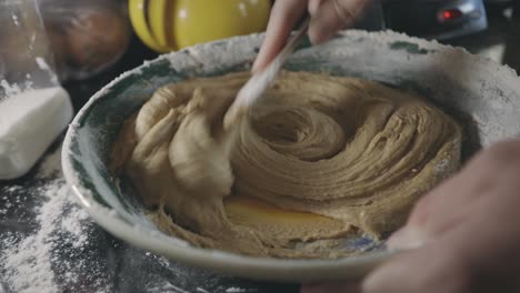 Mixing-Thick-Cookie-Batter-In-A-Bowl-With-Wooden-Spoon---close-up