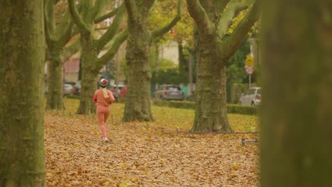 Young-Woman-Runs-In-The-Park-With-Fallen-Leaves-In-Autumn