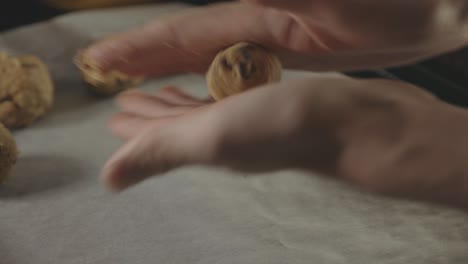 Hands-Rolling-Cookie-Dough-And-Placing-On-Tray-With-Baking-Sheet---close-up