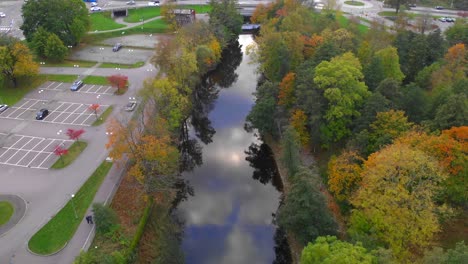 Aerial-view-of-river-running-through-city-with-trees-in-fall-colors