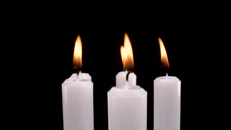 macro-view-rotating-burning-white-candles-on-black-background,-elegant-remembrance-or-memory-of-deceased-footage