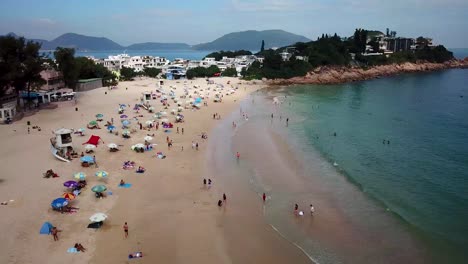 180-degrees-moving-aerial-view-of-visitors-at-Shek-O-beach-in-Hong-Kong-as-public-beaches-reopening,-after-months-of-closure-amid-coronavirus-outbreak,-to-the-public