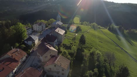 Drone-zoom-in-shot-of-a-typical-mountain-village-in-France-with-sun-flares