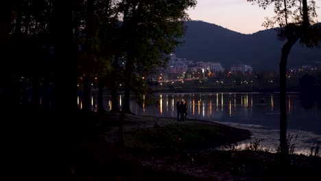 City-park-around-calm-lake-reflecting-street-lights-on-calm-water-at-twilight