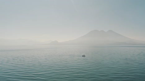 Drone-aerial-flying-towards-a-man-on-a-boat-during-the-morning-in-lake-Atitlan,-Guatemala