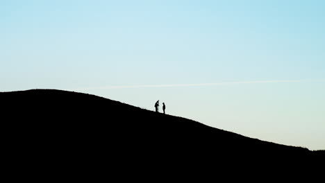 Silhouette-Of-men-doing-topographic-surveyings-on-top-of-black-hill