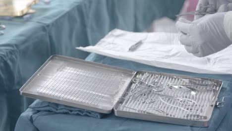 Nurse-preparing-stainless-steel-wire-on-tweezers-on-little-table