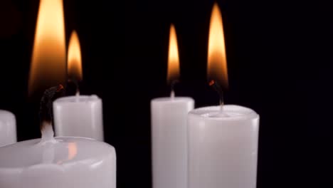 macro-view-rotating-white-candles-on-black-background,-elegant-remembrance