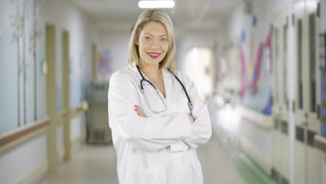 Feliz-Y-Atractiva-Doctora-Rubia-Gira-Y-Sonríe-En-Un-Pasillo-Del-Hospital