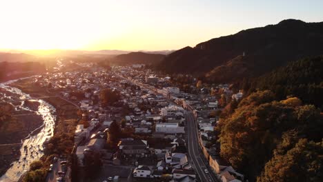 Slow-aerial-drone-flight-over-beautiful-town-silhouette-at-sunrise-with-river