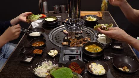 Couple-Enjoying-Korean-Pork-Belly-Barbeque-In-A-Restaurant---close-up-shot