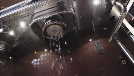 Slowmotion-rinsing-coffee-machine-with-hot-steam-reflecting-in-the-silver-steel-machinery